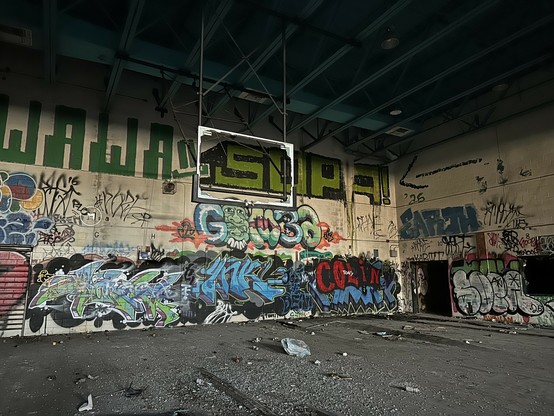 big wall covered in colorful graffiti in what used to be the middle school gymnasium