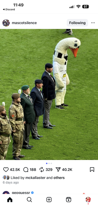 military dudes lined up having a moment of silence next to a giant fuckin swan costume 
