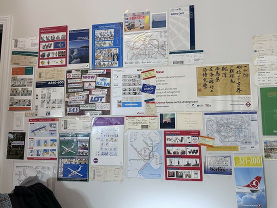 wall full of in flight safety cards, airplane tickets, transit maps, postcards, and other travel ephemera