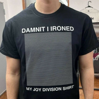 A guy wearing a parody Unknown Pleasures t-shirt with straight, horizontal, white lines that reads "Damnit I ironed my Joy Division shirt".